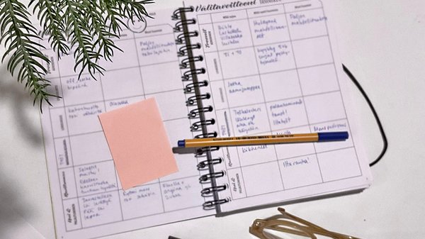 Kalenteri kynä ja muistilappuja pöydällä